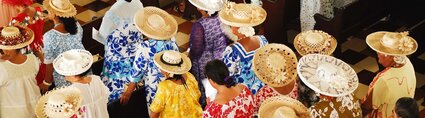 Vue aérienne de chanteurs polynésiens dans une église portant des chapeaux artisanaux